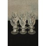 A set nine early 20th century faceted drinking glasses with central knop stem, raised on circular