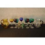 Assorted vintage coloured drinking glasses together glass bells and two glass lemonade jugs. H.19cm.