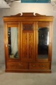 A late 19th/early 20th century pitch pine three door wardrobe, with two mirror doors above two