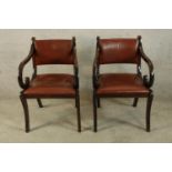 A pair of Regency style mahogany framed and red leather open arm chairs raised on sabre supports.