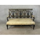 A 19th century ebonised and mother of pearl three seater pierced splat back open arm settee raised