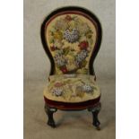 A 19th century lacquered spoonback nursing chair in needlepoint beaded upholstery raised on cabriole