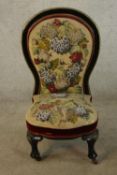 A 19th century lacquered spoonback nursing chair in needlepoint beaded upholstery raised on cabriole