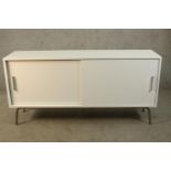 A contemporary white Formica veneered two sliding door cabinet raised on tubular metal supports. H.