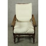 An Arts and Crafts oak framed reclining chair raised on turned supports with loose cushions. H.98