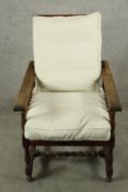 An Arts and Crafts oak framed reclining chair raised on turned supports with loose cushions. H.98