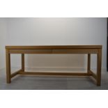 A contemporary oak four drawer refectory style table raised square supports united by a stretcher