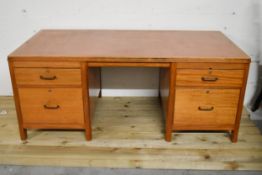 A mid century vintage teak pedestal desk with inset leather top on block supports.