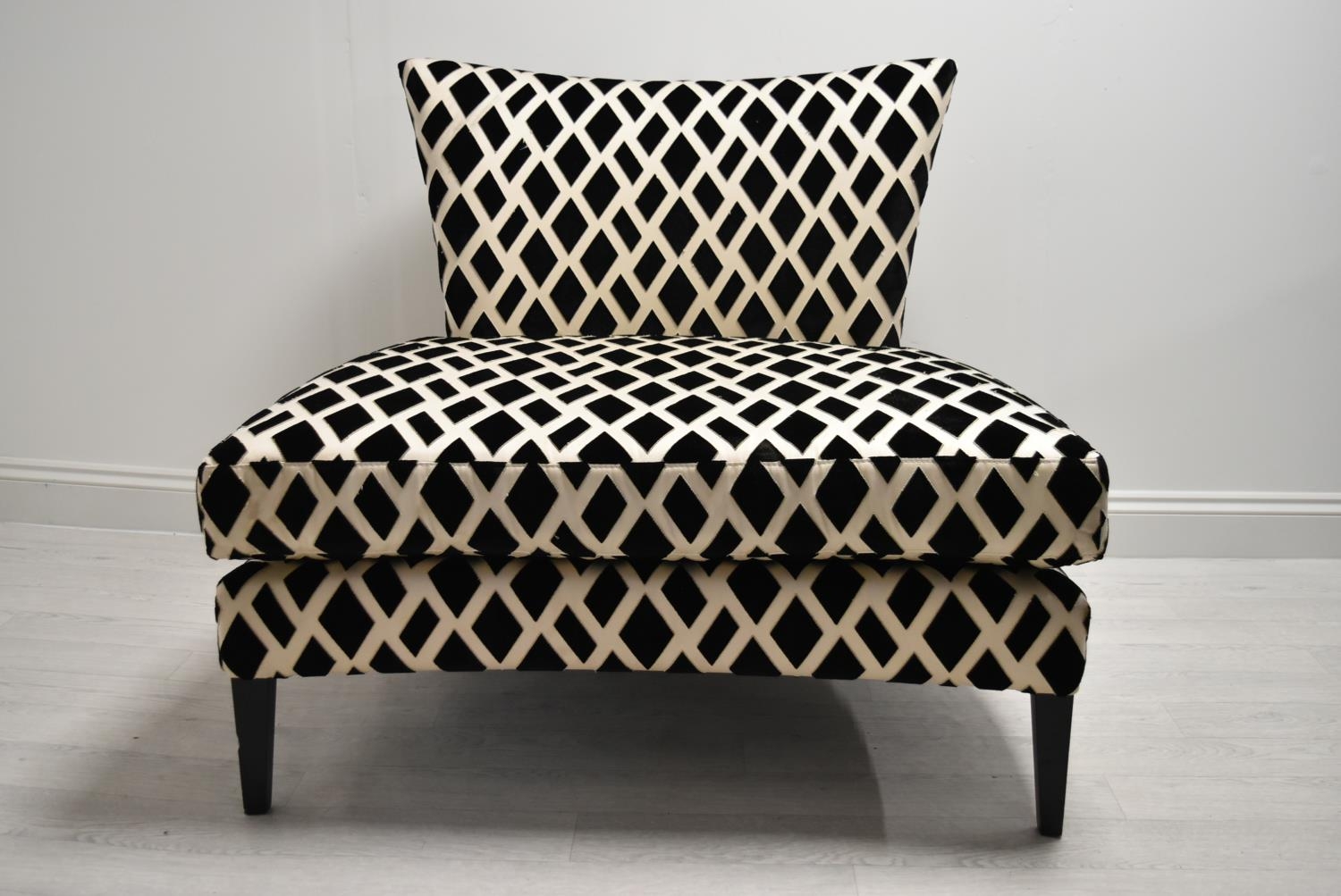 A contemporary black and white designer chair with loose cushions raised on tapering supports. H.