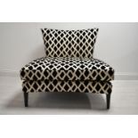 A contemporary black and white designer chair with loose cushions raised on tapering supports. H.