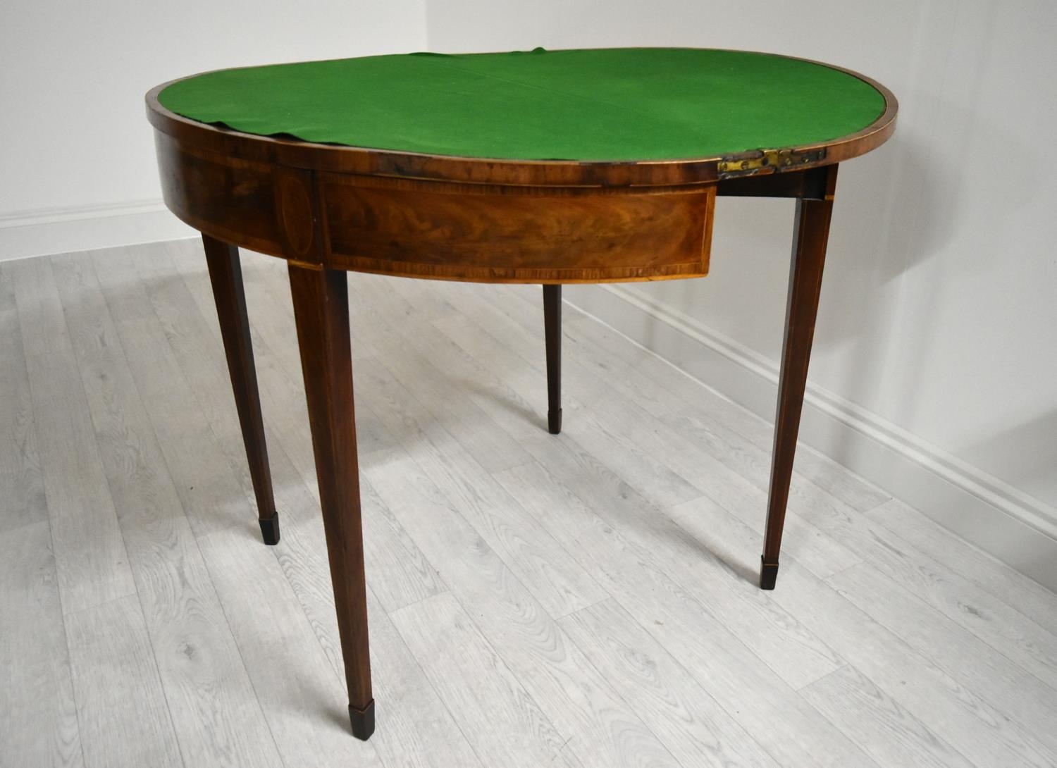 A George III cross banded mahogany fold over demi lune games table, raised on square tapering - Image 4 of 12