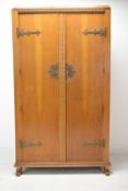 An early 20th century Gothic style carved mahogany twin door wardrobe with brass strapwork hinges