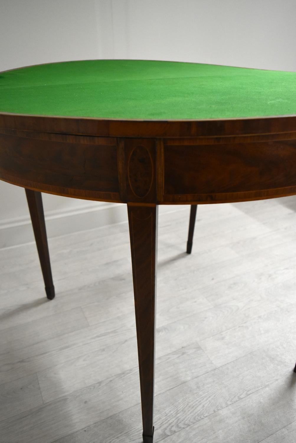 A George III cross banded mahogany fold over demi lune games table, raised on square tapering - Image 7 of 12