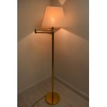 A contemporary brass plated standard lamp with adjustible arm with extension and shade raised on
