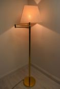 A contemporary brass plated standard lamp with adjustible arm with extension and shade raised on