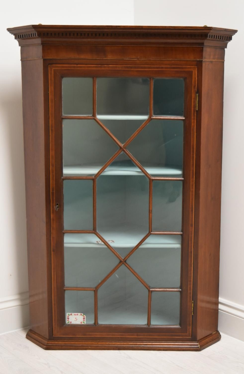 A George III mahogany single door corner cupboard with dentil cornice and single astragal glazed