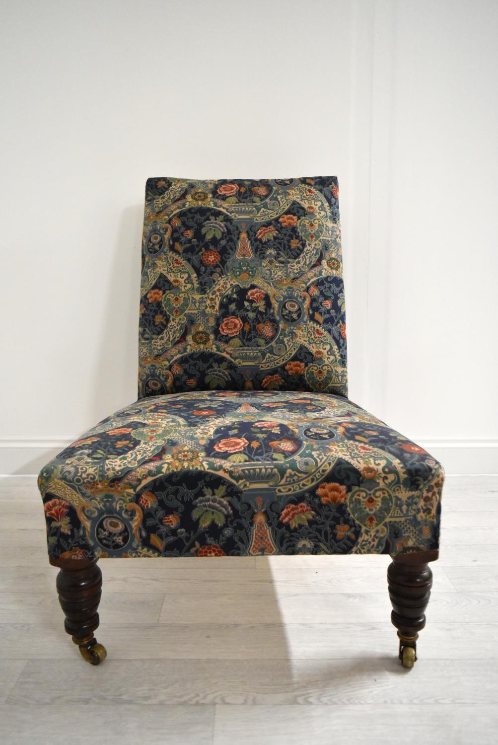 A late 19th / early 20th century mahogany framed and upholstered nursing chair raised on turned