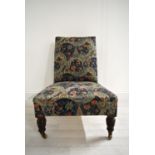 A late 19th / early 20th century mahogany framed and upholstered nursing chair raised on turned