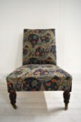 A late 19th / early 20th century mahogany framed and upholstered nursing chair raised on turned