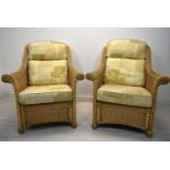 A pair of contemporary cane conservatory armchairs each with loose cushions. H.98 W.82cm