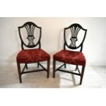 A pair of mahogany framed Hepplewhite style shield back dining chairs, each with stuff over seats.
