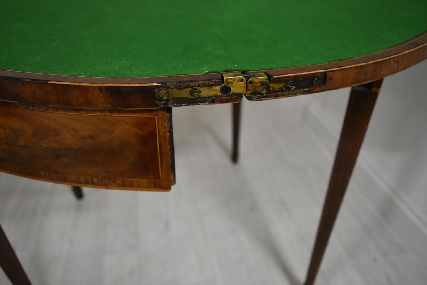 A George III cross banded mahogany fold over demi lune games table, raised on square tapering - Image 6 of 12