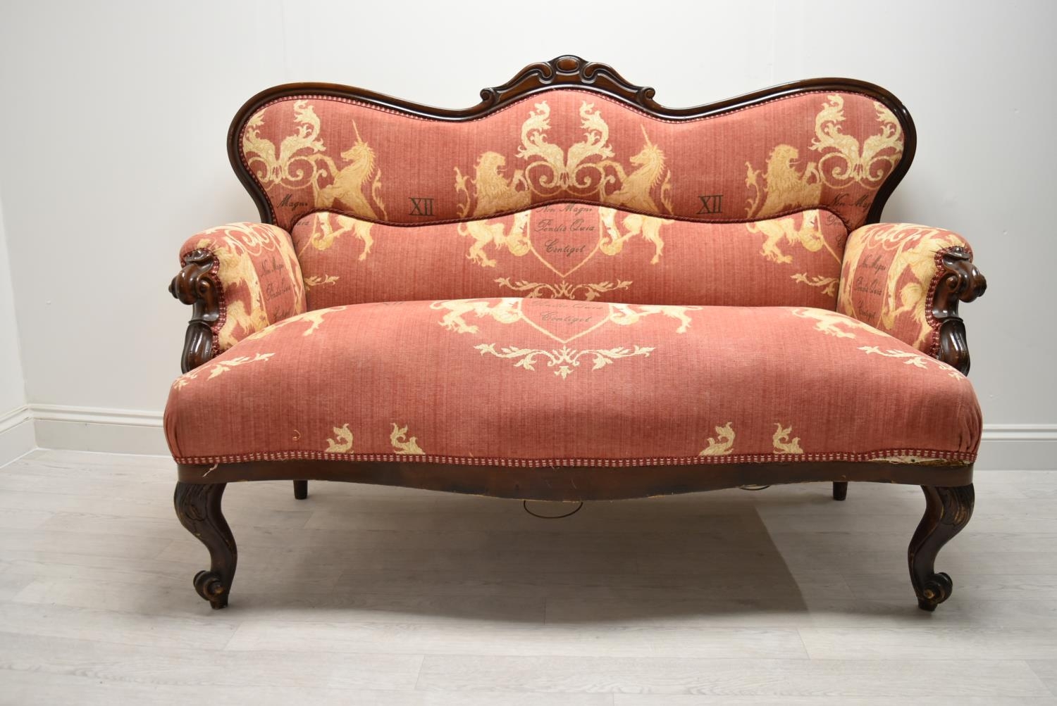 A late 19th / early 20th century mahogany framed French style settee with scroll arms raised on