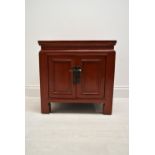 A Chinese style red painted twin door bedside cupboard opening to reveal shelves and single