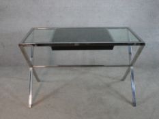 A contemporary chrome plated and glass topped Porado style writing table raised on X shaped