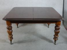 A 19th century mahogany extending dining table raised on heavily carved turned supports