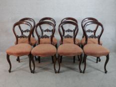 A set of eight Victorian mahogany framed balloon back dining chairs with stuff over seats raised