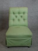 An Edwardian green button back upholstered low nursing chair raised on turned supports.