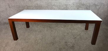A contemporary glass topped table raised on four mahogany square supports. H.76 x W.250 x D.100 cm.