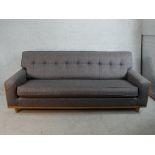 A 20th century G-Plan teak framed grey button back upholstered settee raised on tapering supports.