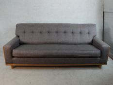 A 20th century G-Plan teak framed grey button back upholstered settee raised on tapering supports.