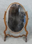 A 19th century mahogany framed oval dressing table mirror raised on outswept supports. H.56 W.33 D.
