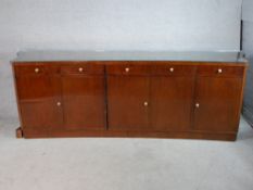 A large mahogany effect sideboard with five drawers above five cupboard doors raised on plinth base.