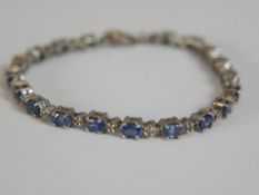 A silver sapphire and rough cut diamond tennis bracelet, set with nineteen oval mixed cut