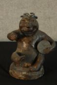 A 20th century Studio pottery figure of a seated man with a drum, with copper lustre finish. H.28cm.