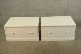 A pair of white single drawer storage units with turned knob handles raised on plinth bases. H.39