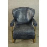 A contemporary brass framed open arm chair upholstered in blue crocodile skin effect material raised