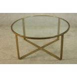 A contemporary circular brass framed glass topped low table raised on X shaped base. H.47 Dia.97cm.