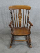 An early 20th century beech childs rocking open arm Windsor chair with spindle and pierced splat