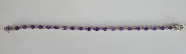 A boxed silver and amethyst tennis bracelet with push clasp and safety catch. Set with twenty one
