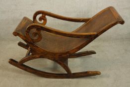 A contemporary teak framed open arm and rattan seated plantation style rocking chair.