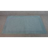 A contemporary John Lewis duck egg blue handmade woollen rug. W.108 L.169cm