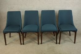 A set of four teak framed upholstered dining chairs raised on tapering supports.