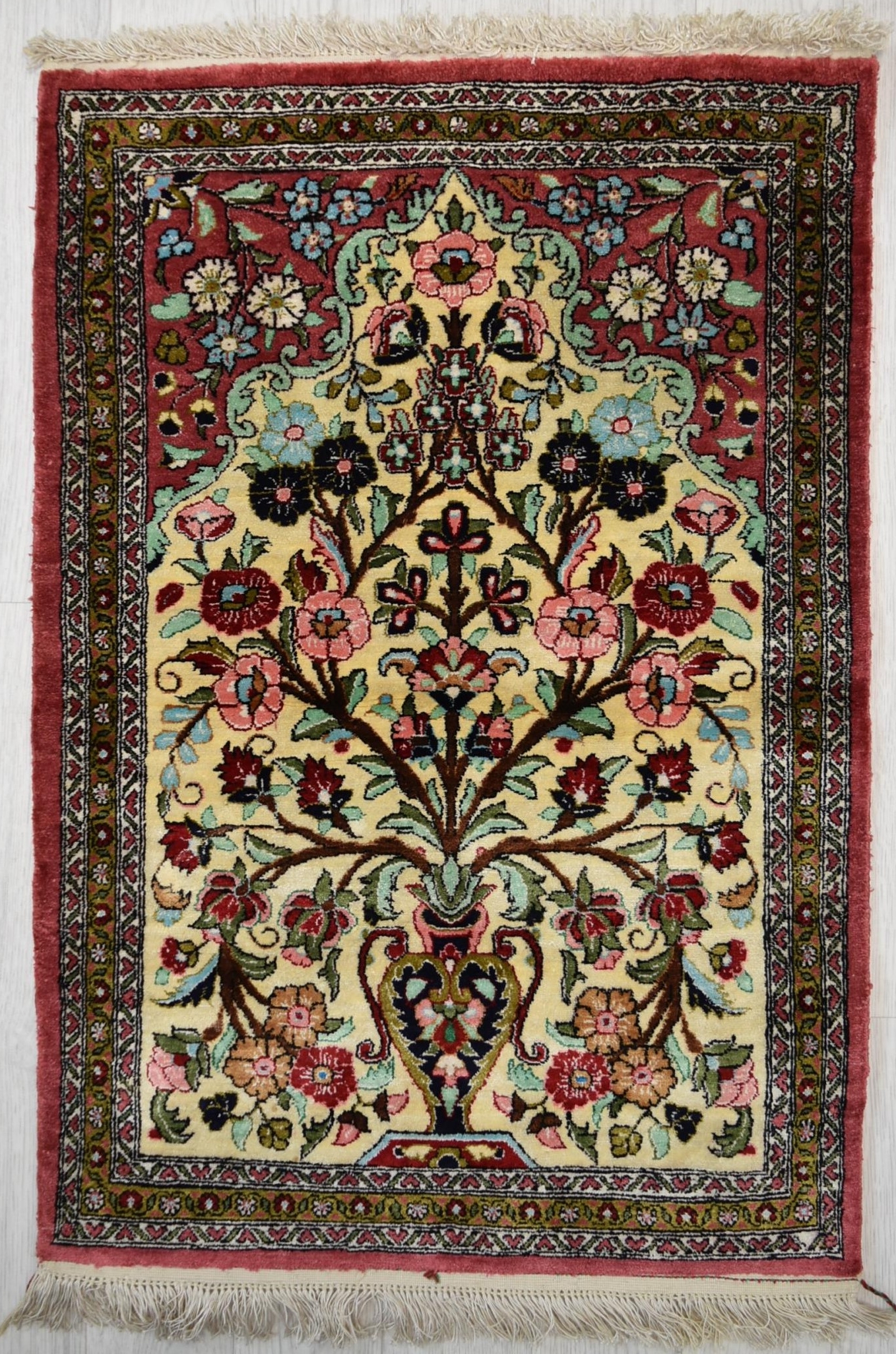 A Persian/Iranian silk qum rug, the central ivory field with tree of life within geometric and