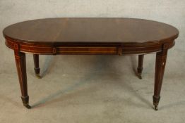 An Edwardian inlaid mahogany D end extending dining table on tapering supports terminating in