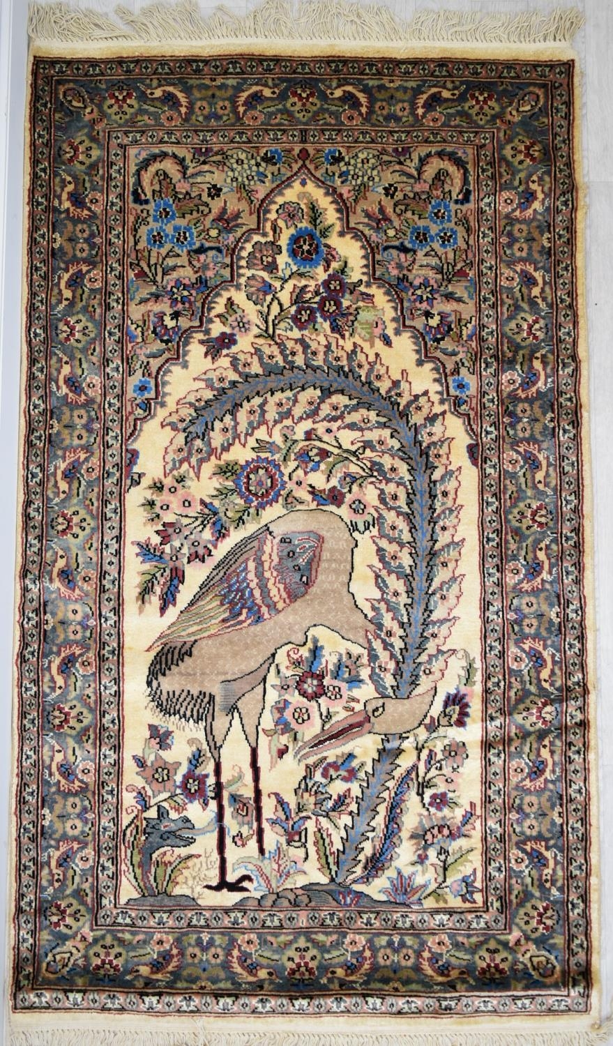 A Persian silk and wool tree of life rug, the ivory field with a crane and assorted flowers within a